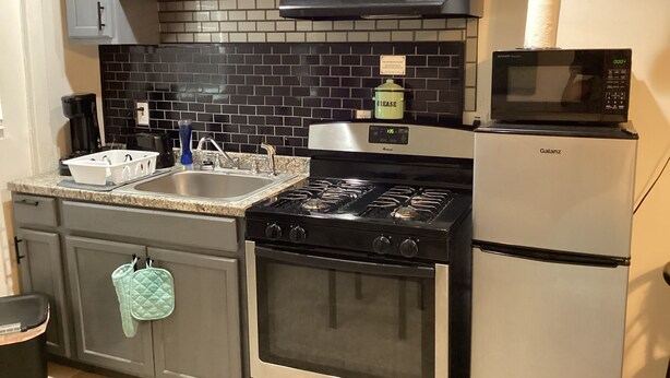 A kitchen with a stove, oven, microwave, sink, and cabinets.