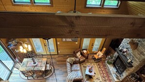 Un vaste espace de vie aménagé dans un style industriel, avec un plafond haut, des poutres en bois et de grandes fenêtres.