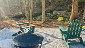 A circular outdoor seating area with two green Adirondack chairs and a round table.