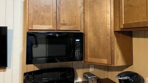 A kitchen with wooden cabinets, a black microwave, a stove, and a toaster.