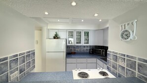 A compact kitchen with a refrigerator, microwave, and stove.