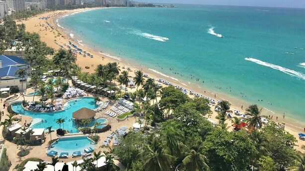 A resort with a large pool area, beach access, and a view of the ocean.