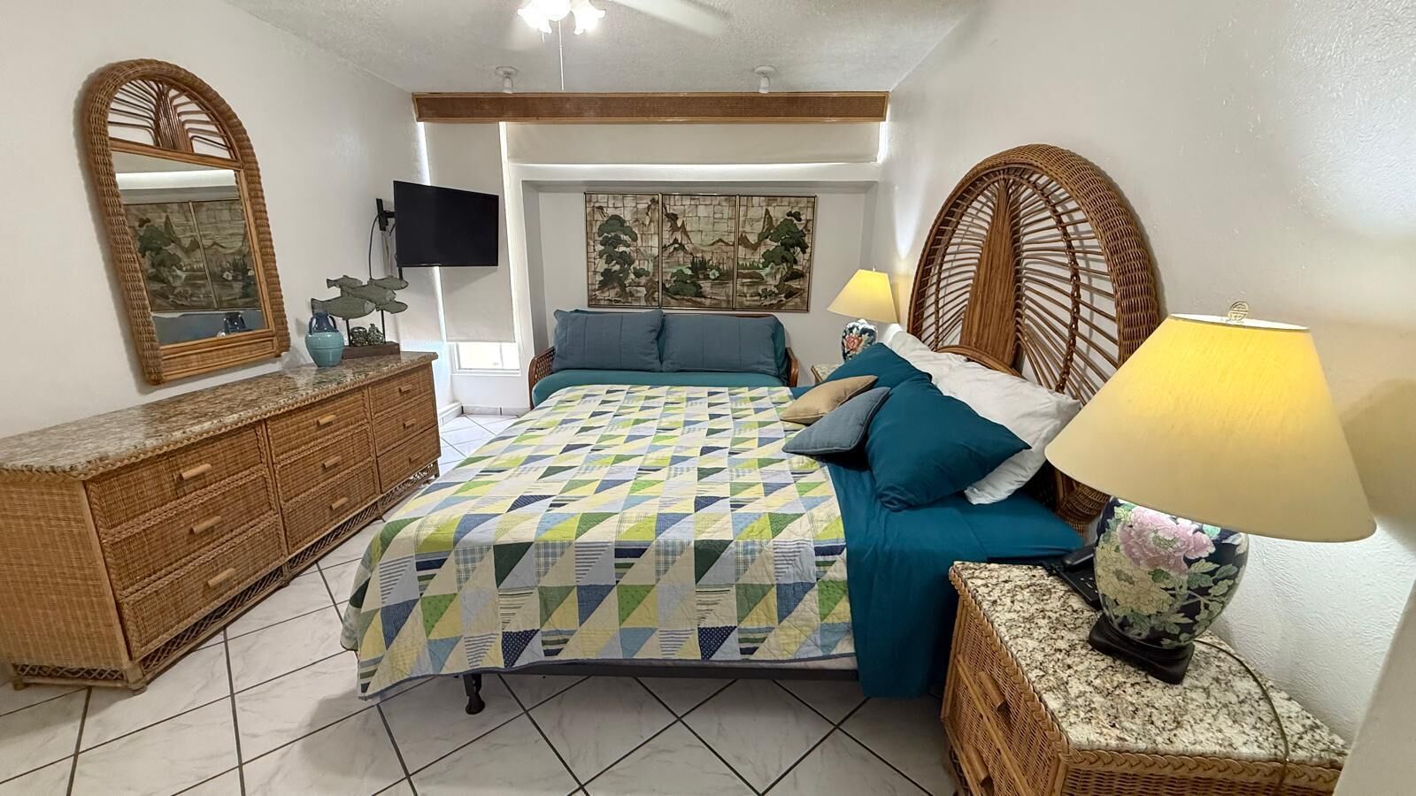 A bedroom with a bed, a dresser, a television, and a wall-mounted artwork.