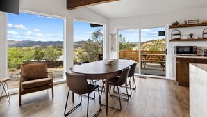 A spacious dining area with a large table and chairs, a wooden bench outside, and a kitchen area with a microwave and shelves. - The Sanctuary at Prescott Heights |Majestic Views |Luxe Prescott Sanctuary |Golf (Prescott)