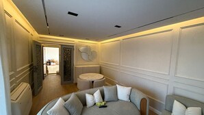 A modern, well-lit room with a curved sofa, a round table, and a decorative wall panel.
