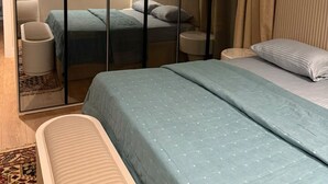 A bedroom with a bed, a nightstand, a chair, a small table, and a wardrobe.