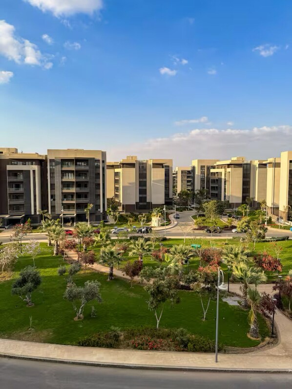 A modern apartment complex with multiple buildings, green lawns, and palm trees.