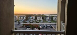 Townhouses with balconies overlook a parking lot and a serene body of water.