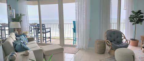 Un salón acogedor con sofá, sillones y vistas al mar a través de amplios ventanales.