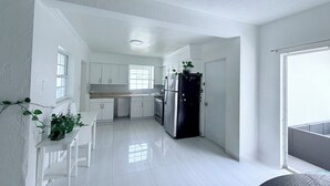 Una cocina compacta con armarios blancos, un refrigerador negro y una ventana que proporciona luz natural.