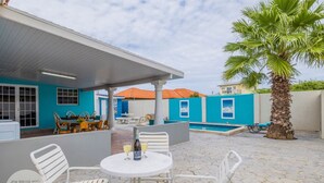 A patio area with a pool, outdoor seating, and a palm tree. - Cinderella Oasis (Noord)