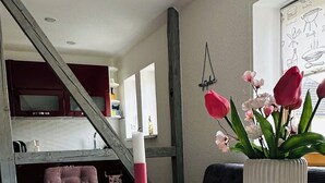 Un tavolo da pranzo con una candela, un vaso con fiori e una tovaglia bianca decorata con motivi floreali.