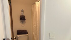 A bathroom with a toilet, a towel rack with towels, a shower curtain, and a sink with a cabinet.