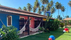 A colorful house with a red door, a hammock, and a clear blue sky.