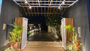 A modern entrance with a wooden pergola, potted plants, and a sign reading "Vila Maria."