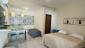 A bedroom with a bed, bedside tables, a desk, chairs, and a tiled floor.
