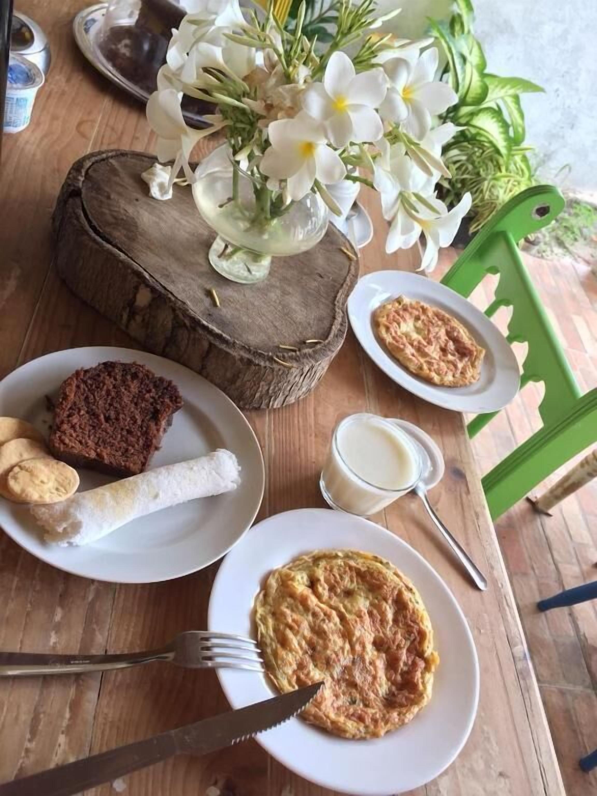 Uma mesa de madeira com um prato de comida, um copo de leite e um garfo.