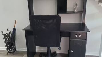 A black office desk with a chair, a globe, and a small statue on the shelf.