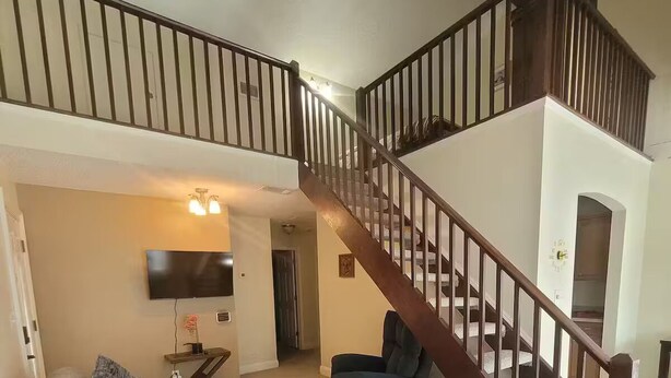 A living room with a grey sectional sofa, a blue armchair, and a wooden staircase.