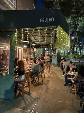 An outdoor café named 'BRUTHO' with tables and chairs arranged for dining.