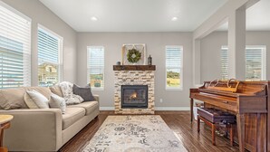 A living room with a fireplace, a sofa, a piano, and a patterned rug.