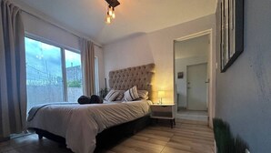 A bedroom with a large bed, a bedside table, a lamp, and a view through a window. - Beautiful apartment with Rooftop in Condesa/Rome (Ciudad de México)