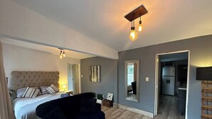 A modern bedroom with a tufted headboard bed, a dark blue sofa, a marble coffee table, and a small side table. - Beautiful apartment with Rooftop in Condesa/Rome (Ciudad de México)