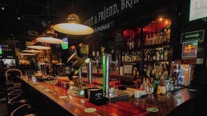 A bar with a long counter, bar stools, and a variety of bottles and glasses. - Beautiful apartment with Rooftop in Condesa/Rome (Ciudad de México)