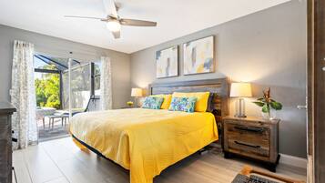 A bedroom with a bed, a ceiling fan, a nightstand, and a view of the outdoors.