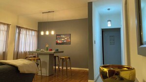 Un salon moderne avec un canapé, un coin repas comprenant une table et des tabourets, un îlot de cuisine et un bol décoratif.
