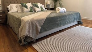 Un lit bien fait, avec une couette grise et blanche, un plaid gris et une serviette blanche posée sur le pied de lit.