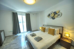 A hotel room with a large bed, two bedside lamps, a wall art piece, and a view through the window. - Luxury penthouse with jacuzzi, sun terrace APIC1-2 (Msida)