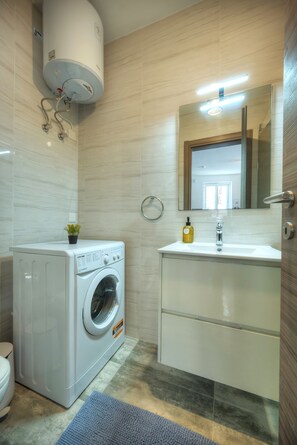 A modern bathroom with a built-in washer and dryer, a sink with a mirror, and a toilet. - Luxury penthouse with jacuzzi, sun terrace APIC1-2 (Msida)