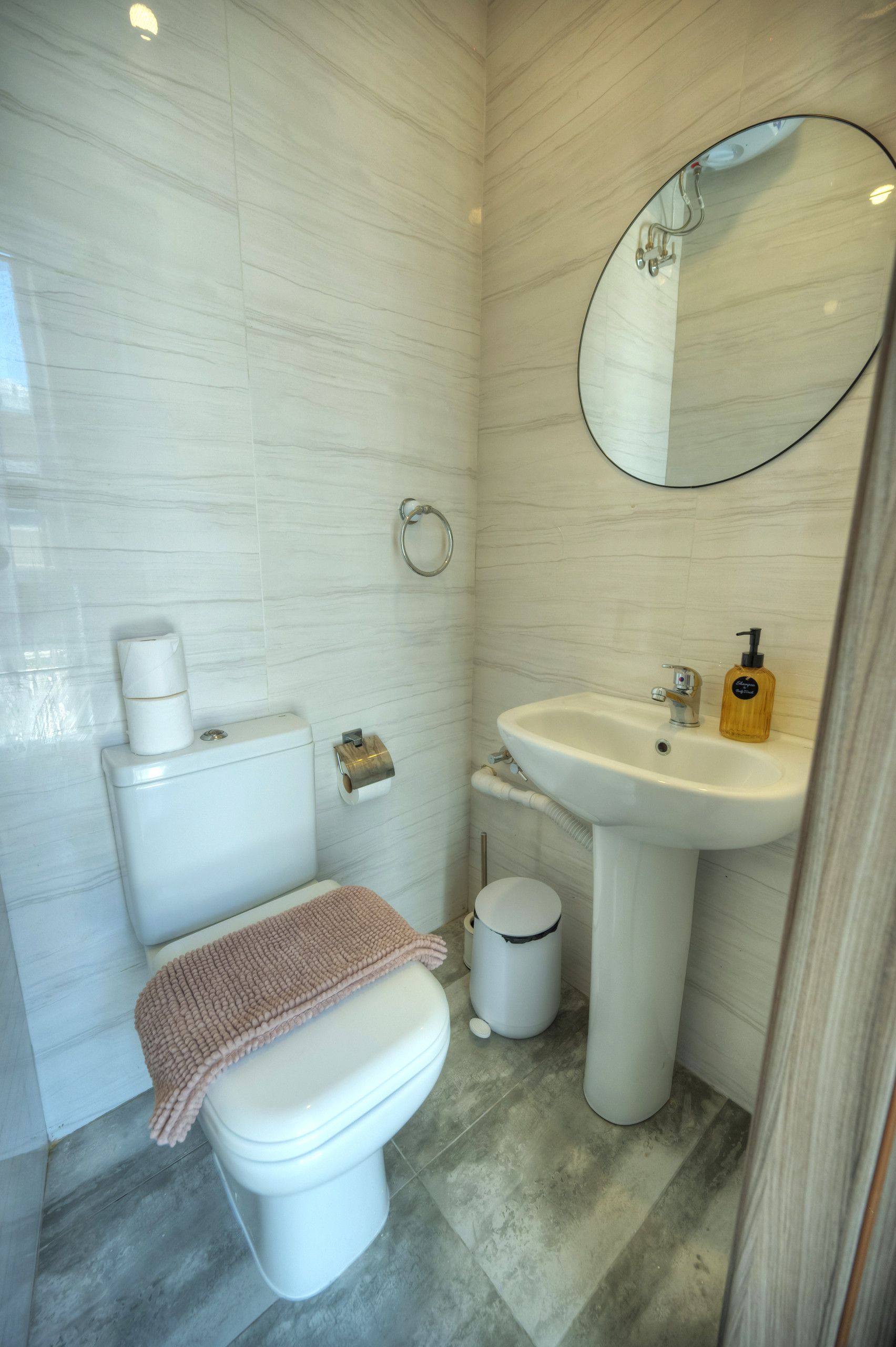 A bathroom with a toilet, sink, and mirror.
