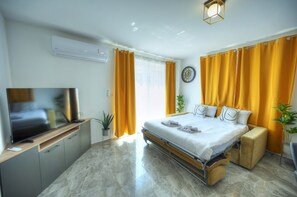 A modern hotel room with a flat-screen TV, a bed with a headboard, a bedside table, and a small seating area. - Luxury penthouse with jacuzzi, sun terrace APIC1-2 (Msida)