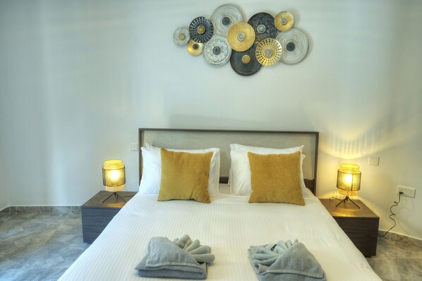A neatly made bed with two pillows, two bedside lamps, and a wall art piece above it. - Luxury penthouse with jacuzzi, sun terrace APIC1-2 (Msida)