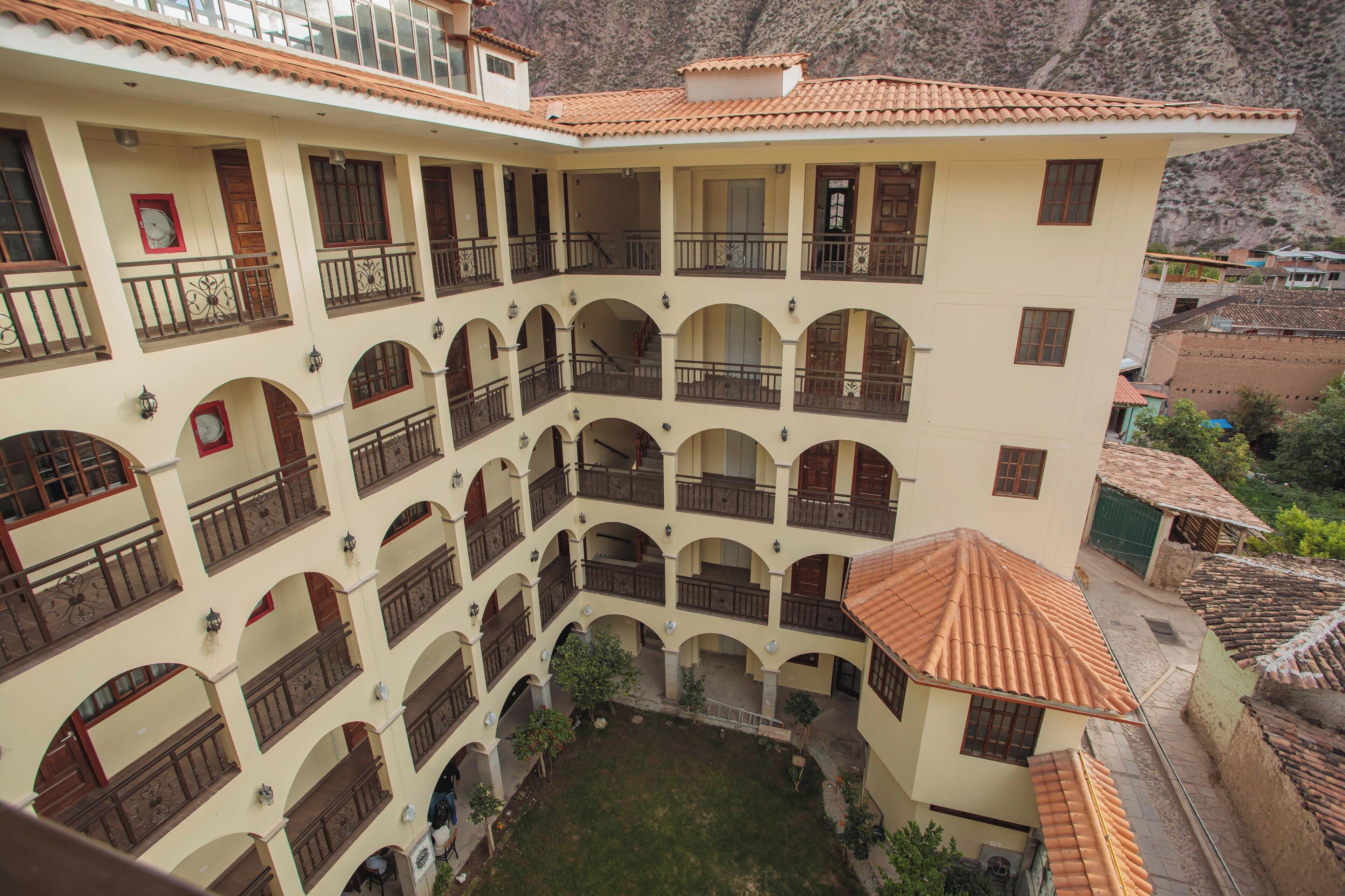 Um edifício de vários andares com um pátio, varandas e telhado em telhas.