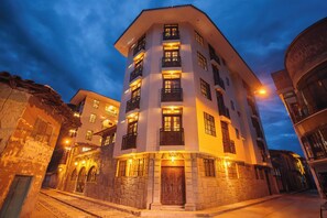 A multi-story hotel with a central courtyard, stone facade, and illuminated windows. - Valle del Sol (Yucay)