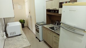Μια μικρή, λειτουργική κουζίνα με εντοιχισμένο φούρνο, νεροχύτη και ψυγείο.