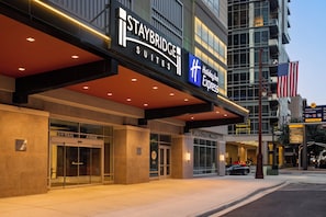 Hôtel Staybridge Suites avec une façade en verre, une enseigne pour le marché urbain « Urban Street Market » et un drapeau américain.