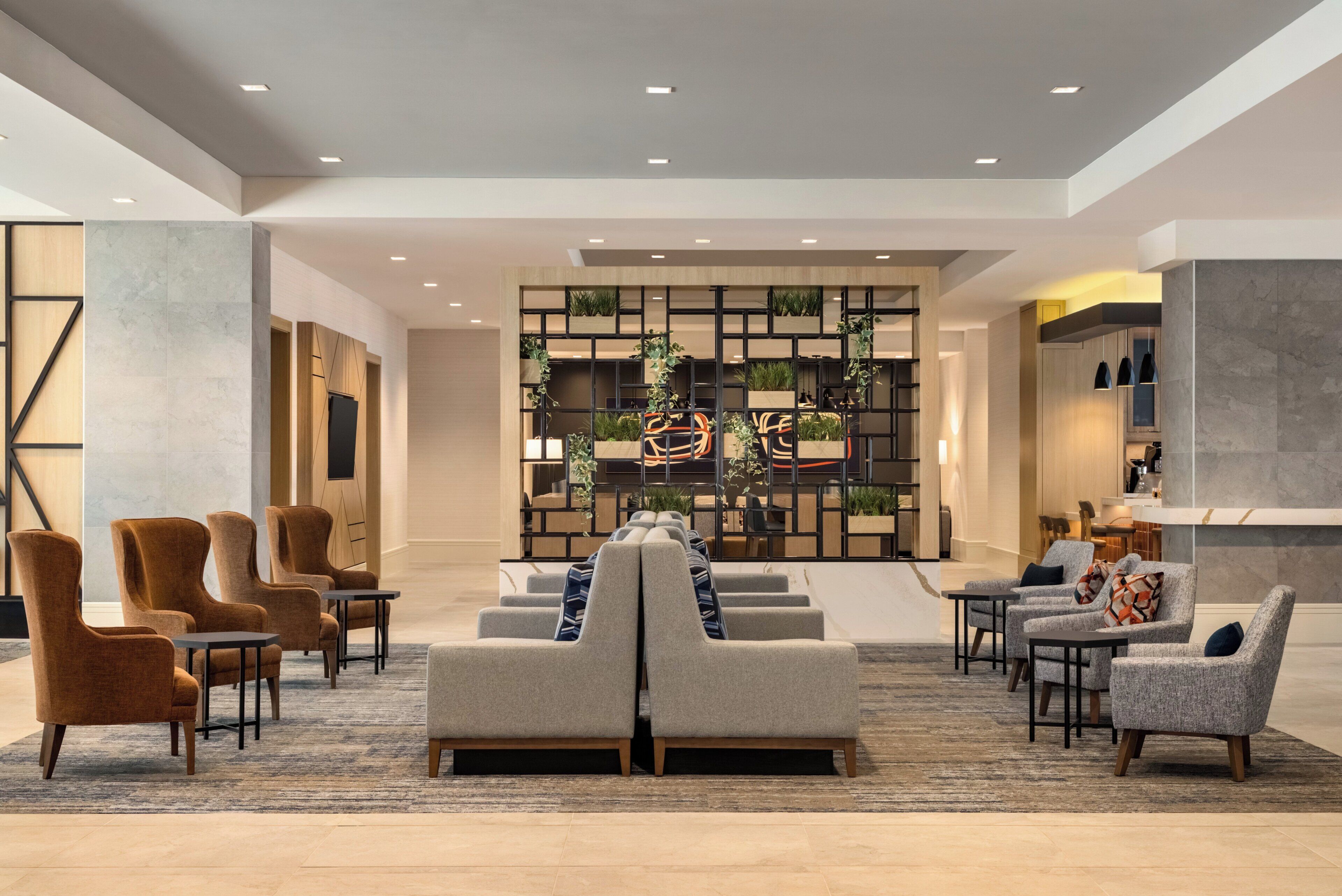 A modern lobby with seating, a reception desk, and a plant wall.