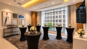 A hotel lobby with round tables, a wine display, and large windows offering a city view. - Holiday Inn Express Houston Downtown by IHG (Houston)