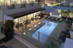 A rooftop pool area with lounge chairs, a seating area, and a glass-enclosed space. - Holiday Inn Express Houston Downtown by IHG (Houston)