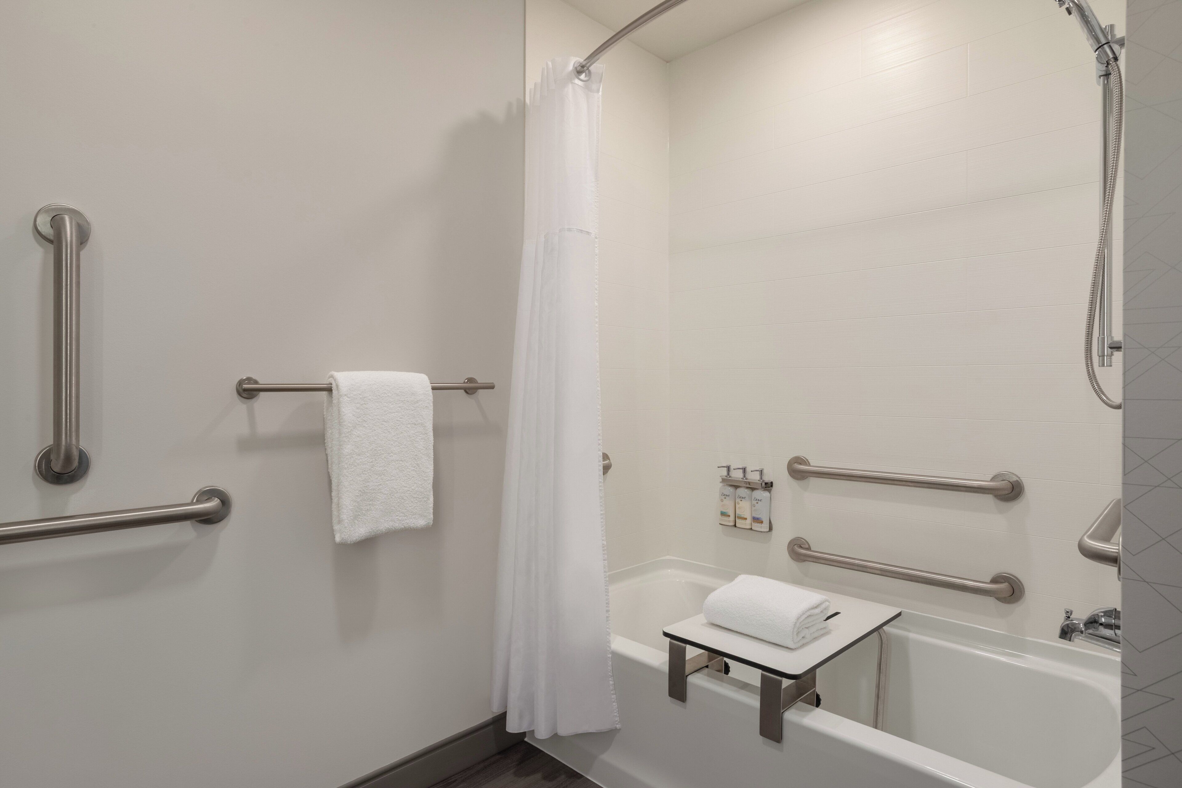 Une salle de bain équipée d’une baignoire, d’une douche et de barres d’appui.