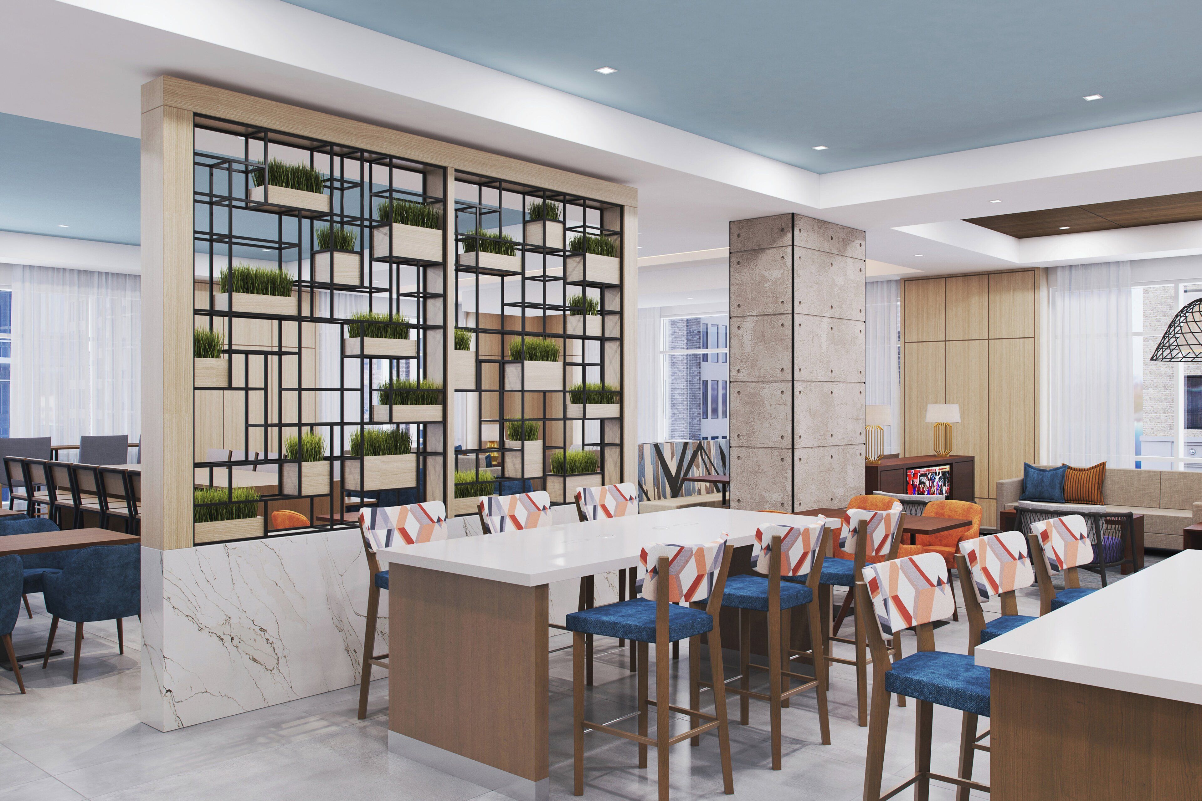 Zona pranzo moderna con un tavolo bianco centrale, circondato da sgabelli da bar con cuscini decorati. Si nota una parete ornamentale con mensole geometriche e piante.