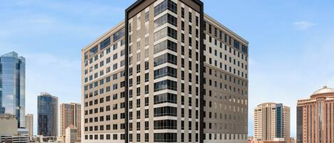A multi-story hotel with a modern design, featuring a prominent corner entrance and a large glass facade.