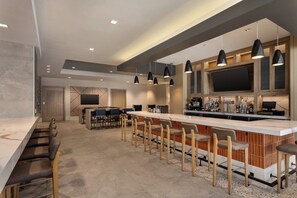 A modern kitchen with a bar area, bar stools, and a flat-screen TV.