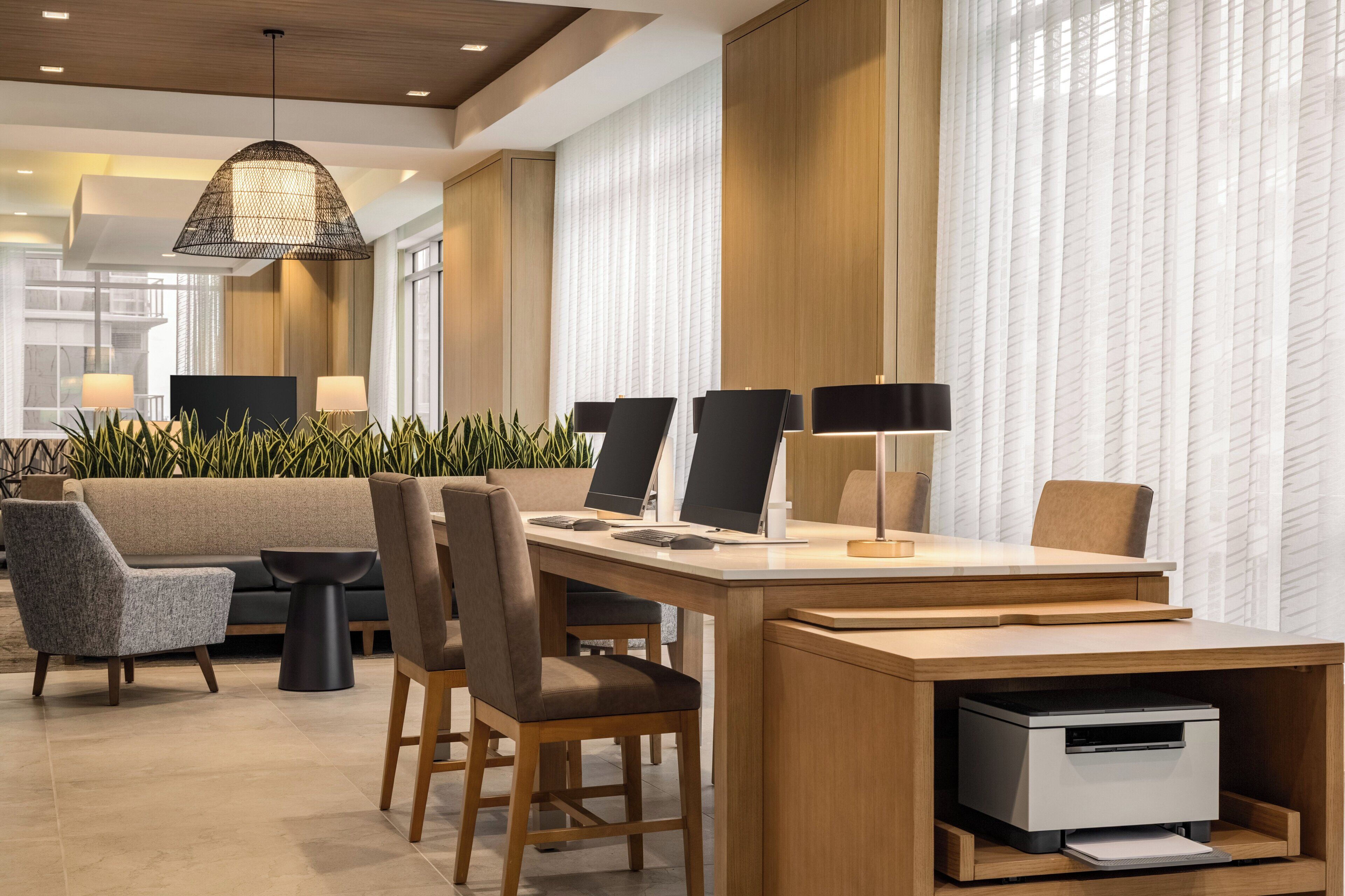 Un moderno vestíbulo de hotel con mostrador de recepción, zona de estar y amplios ventanales.