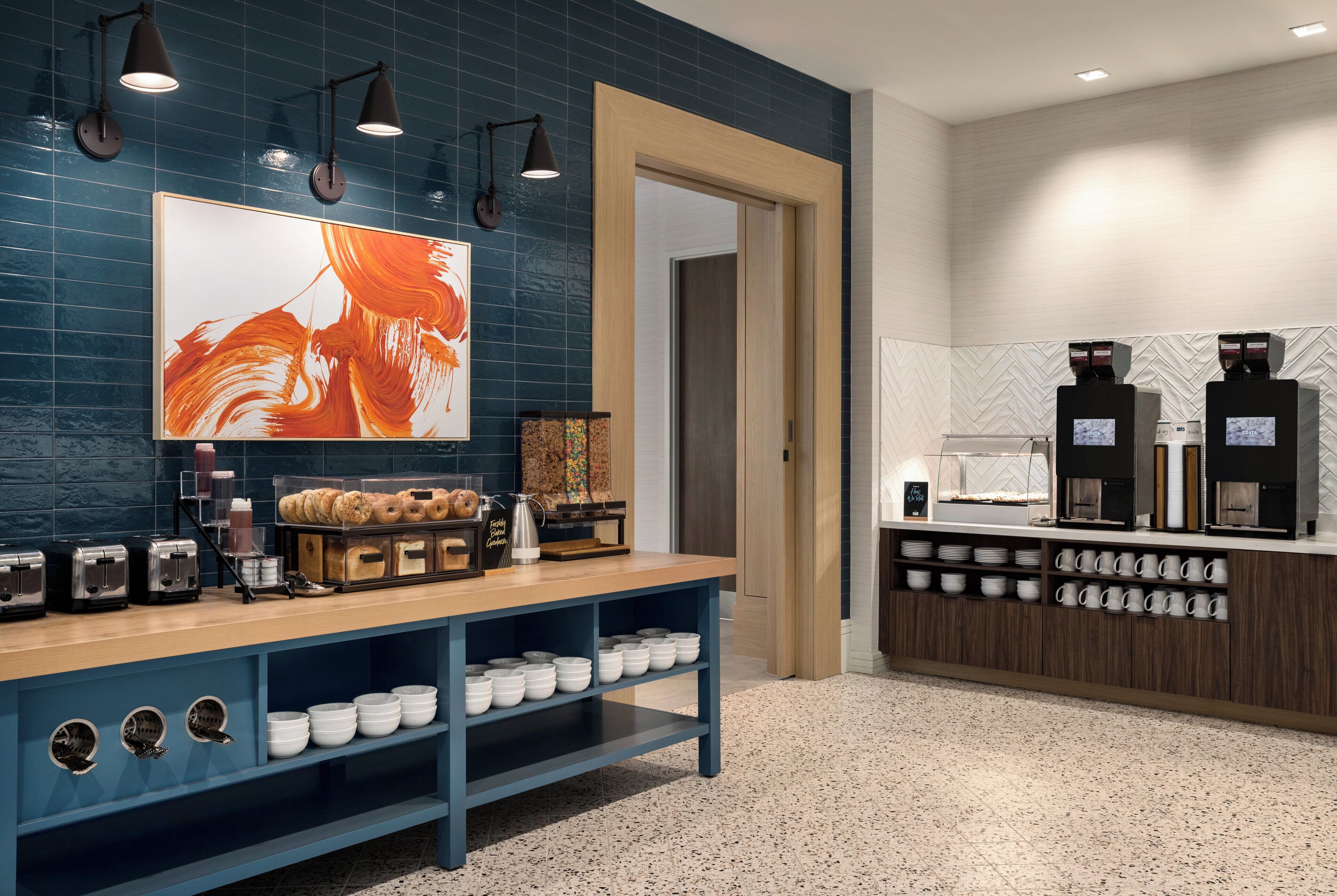 Uma estação de café moderna com balcão, máquinas de café e diversos doces.