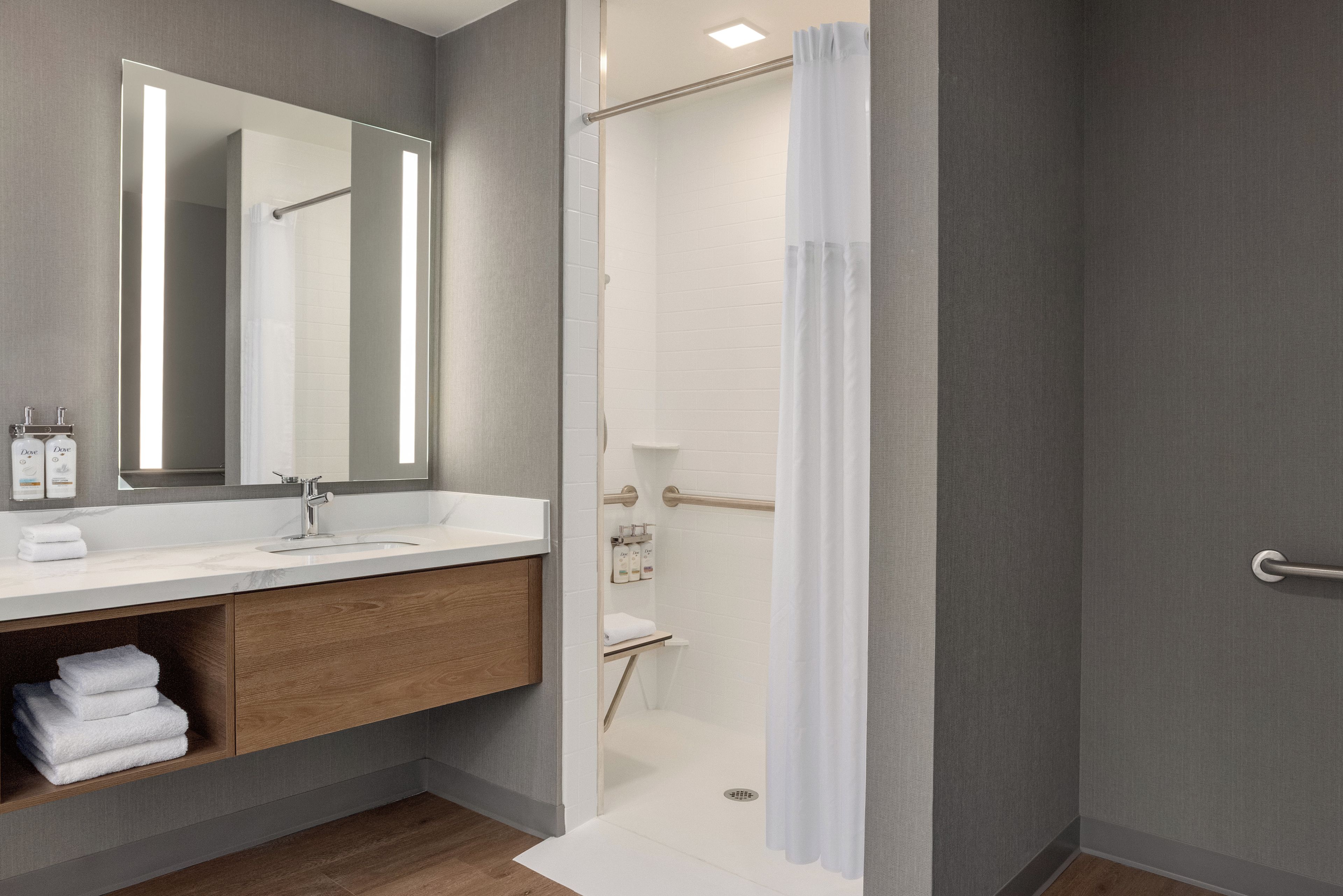 Un baño moderno con un espejo grande, un lavamanos y una zona de ducha.